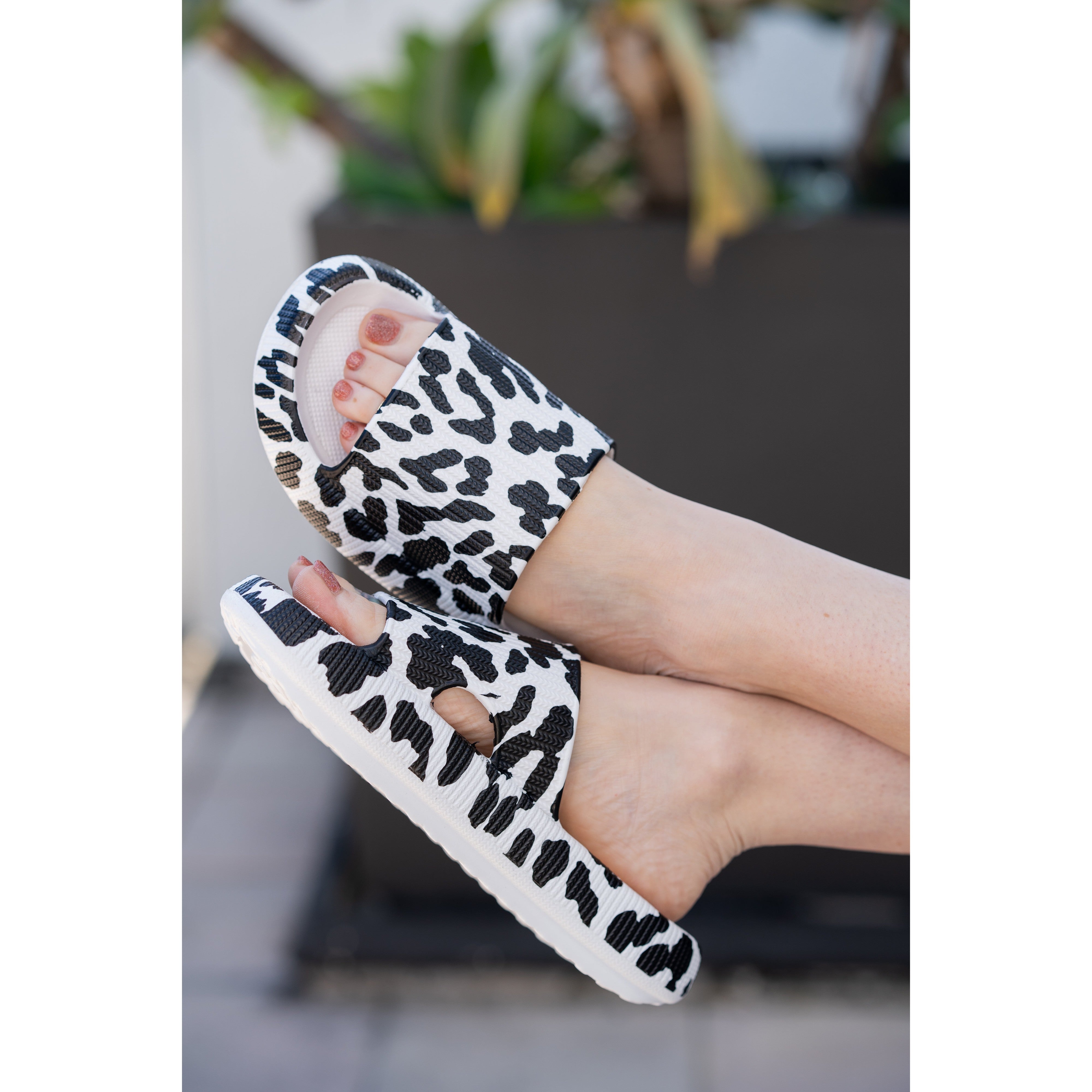White leopard-print beach slides with a bold spotted pattern and easy slip-on design