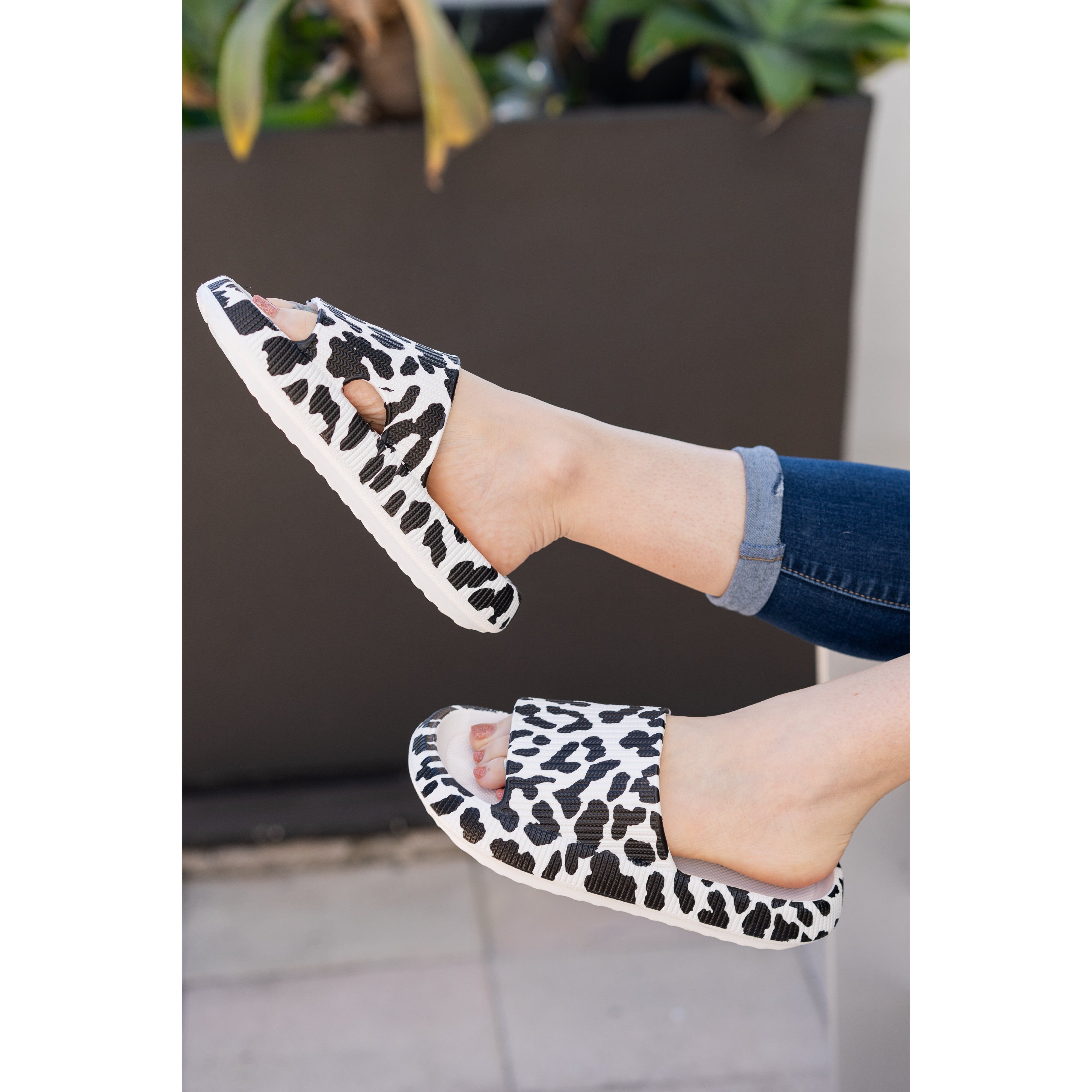 White leopard-print beach slides with a bold spotted pattern and easy slip-on design
