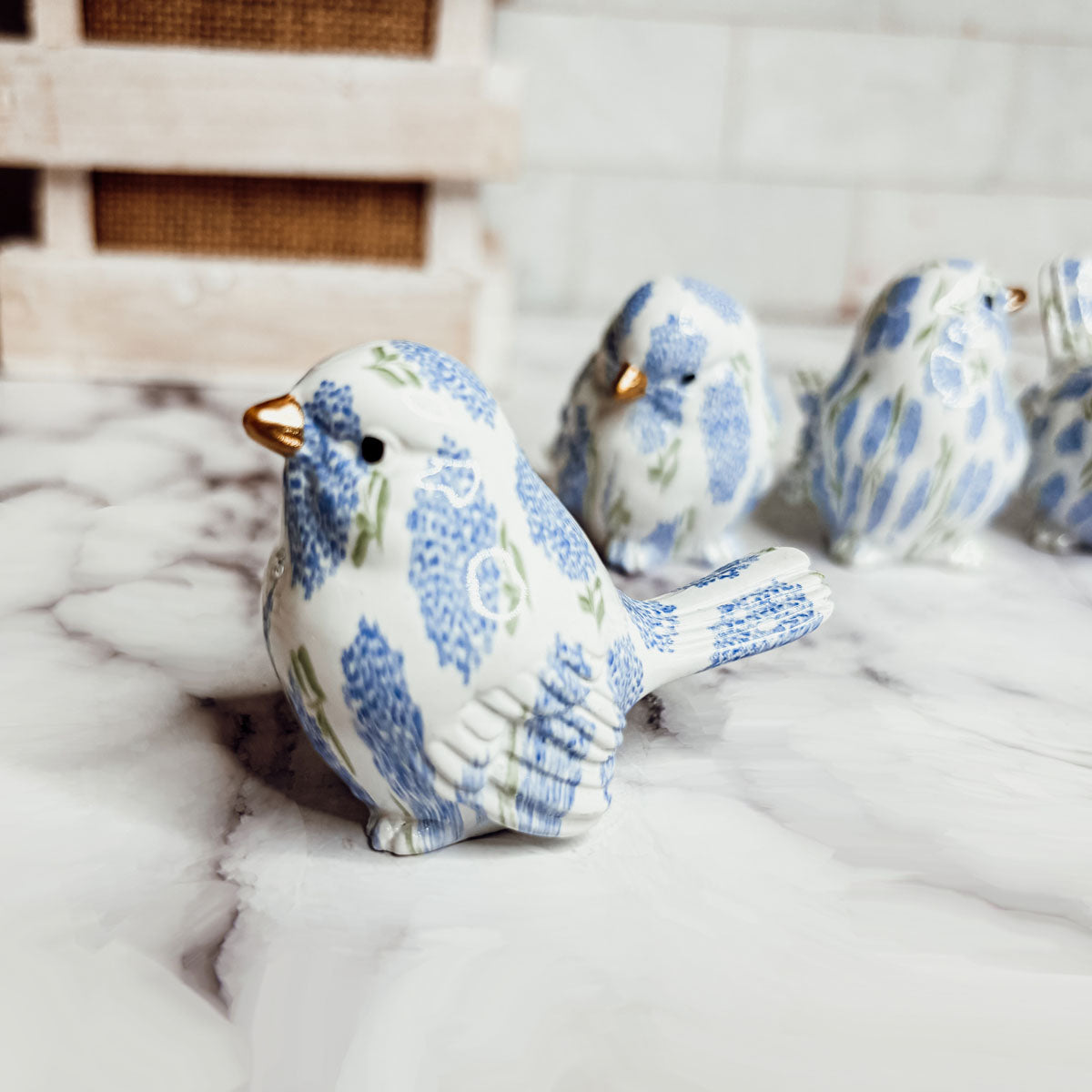 Set of four small resin blue hydrangea bird figurines on a marble surface, perfect for home decor