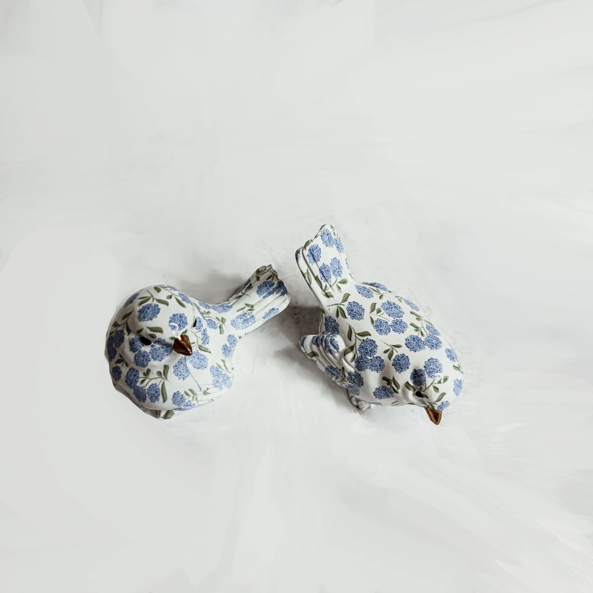 Artistic shot of blue hydrangea bird figurine against a rustic wooden background.