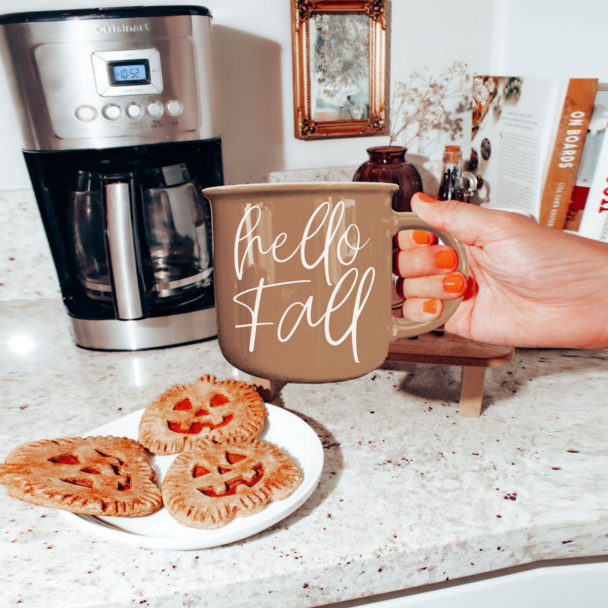 hello fall mug next to stack of sweaters
hello fall coffee cup on kitchen island
hello fall mug on round wooden riser
hello fall mug with neutral fall tablescape
hello fall mug by fireplace with stacked wood
hello fall mug next to pumpkin bread loaf
hello fall mug as part of autumn self care setup
